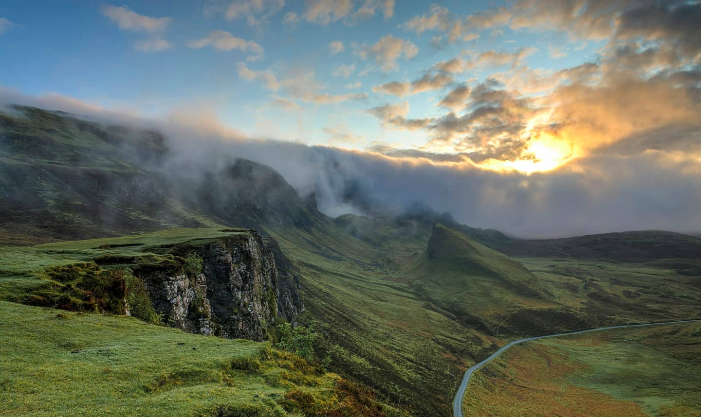 Mist over green clifftops at sunrise